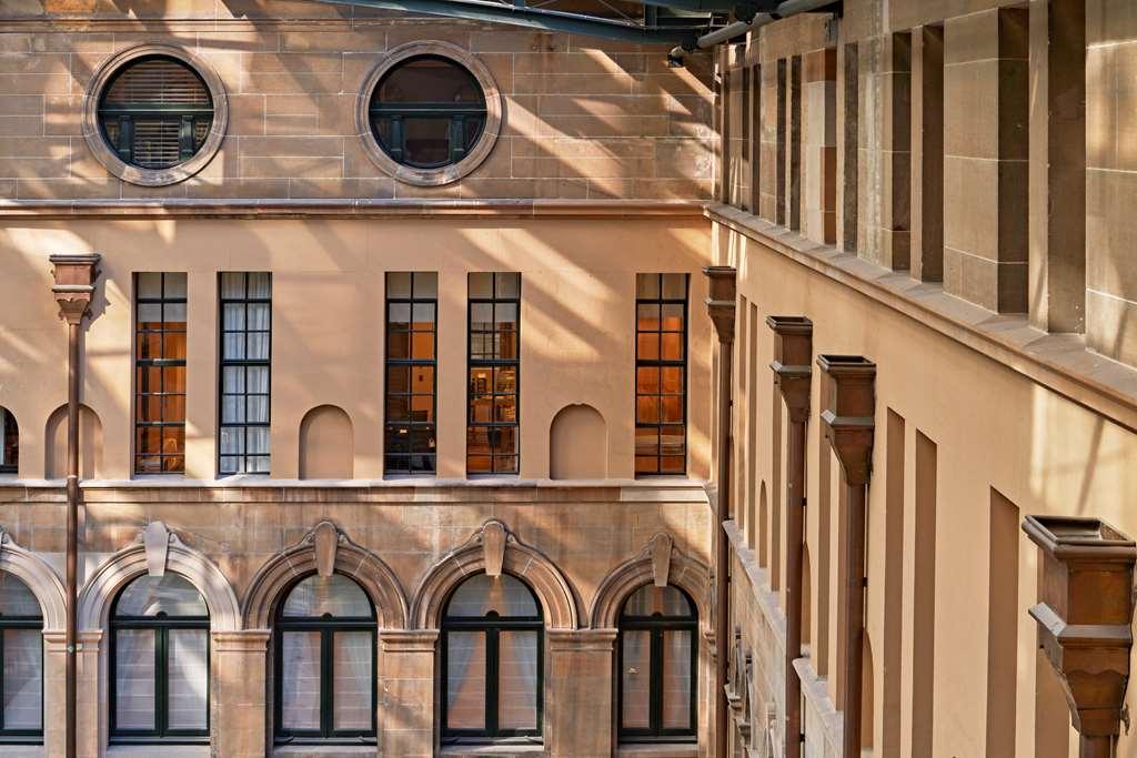 The Fullerton Hotel Sydney Interior foto The photo shows an architectural interior featuring a wall with large windows, showcasing a mix of rounded and rectangular shapes. The building materials appear to be a light-colored stone, and the play of light and shadow adds depth to the scene. Th