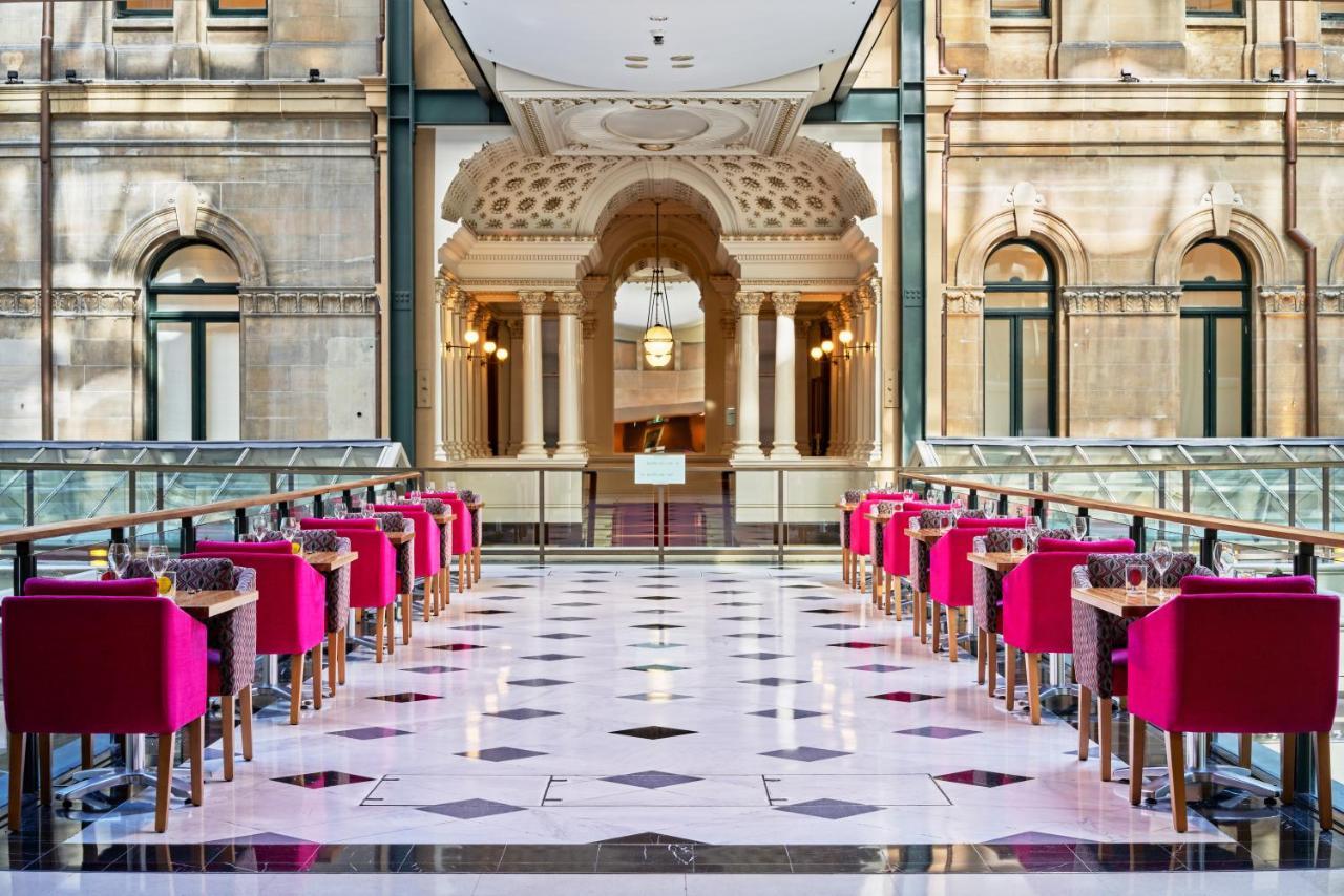 The Fullerton Hotel Sydney Exterior foto The photo shows a stylish and elegant interior of a restaurant or café. There are several tables arranged in a row, each accompanied by bright pink chairs. The flooring features a checkerboard pattern with black and white tiles. In the background, th