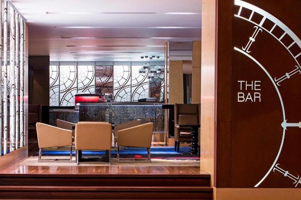 The Fullerton Hotel Sydney Exterior foto The photo shows a modern bar area with a stylish and elegant design. In the foreground, there are several upholstered chairs arranged around a small table. The bar counter is visible in the background, featuring a sleek design and various lighting el